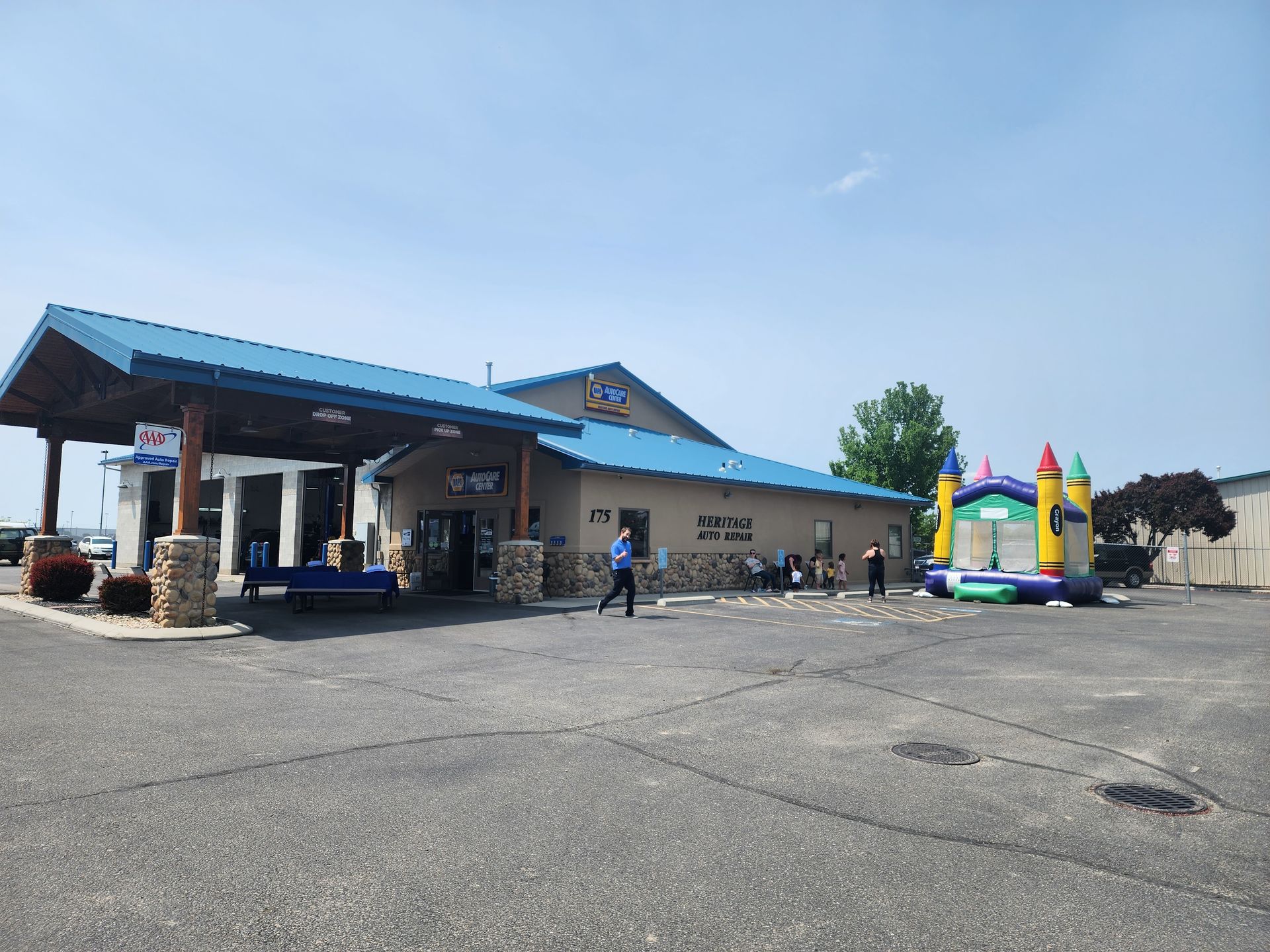 Small building with blue roof and colorful inflatable bounce house on a sunny paved lot.