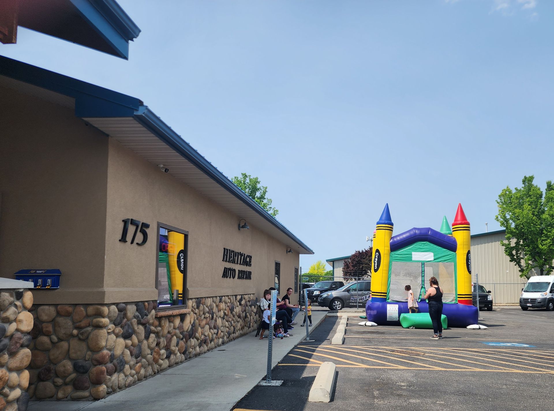 Children in a colorful inflatable bounce house outside a building on a sunny day.