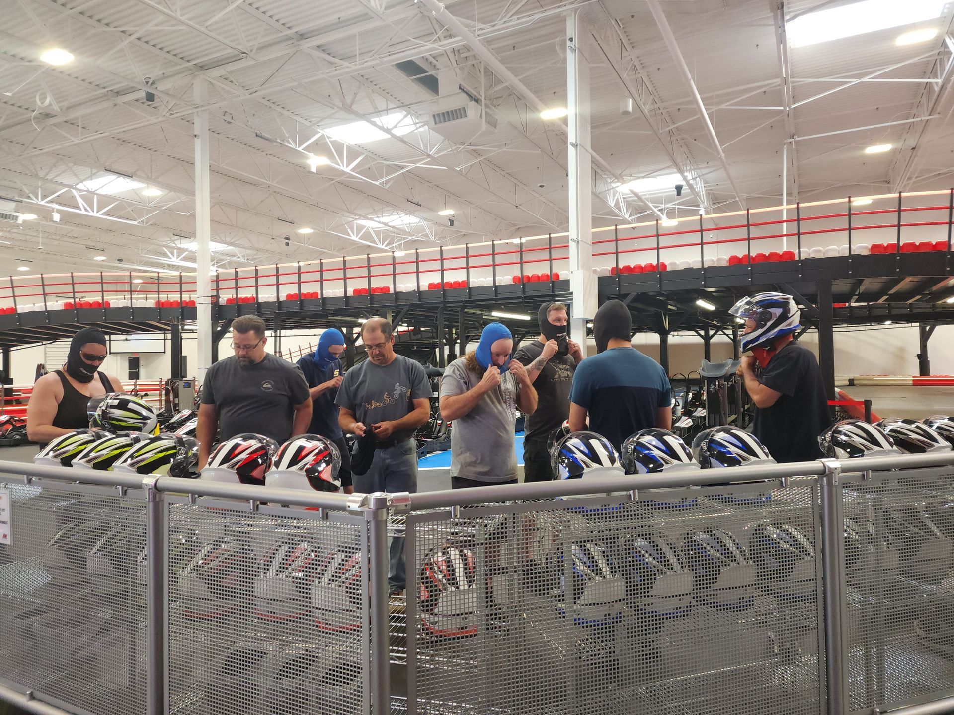People gathered around rows of go-karts in a brightly lit indoor track facility.