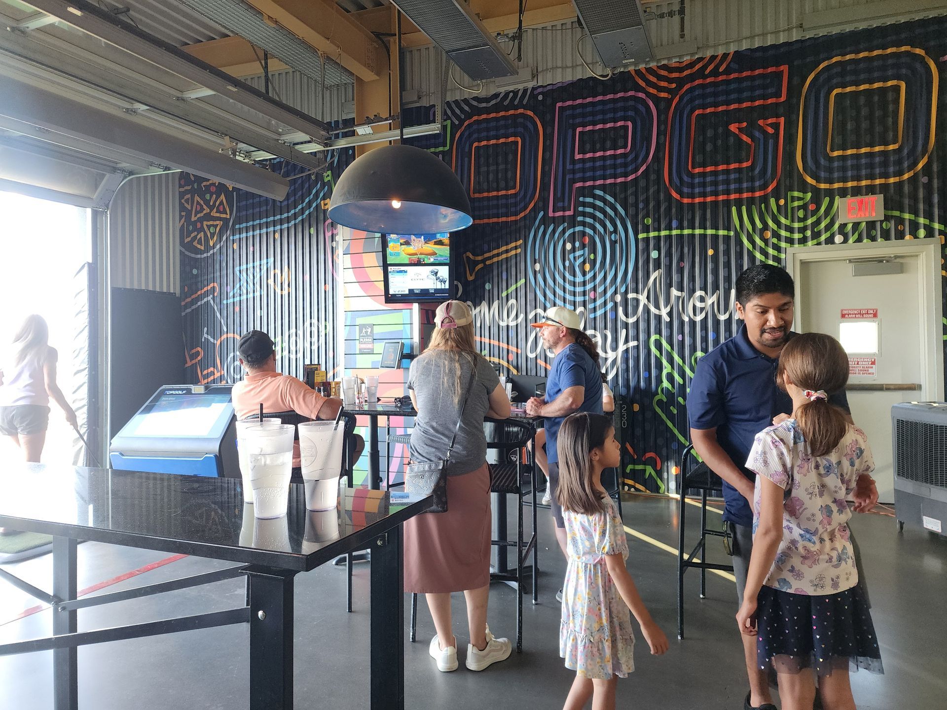People at a neon-lit arcade counter, with a large.