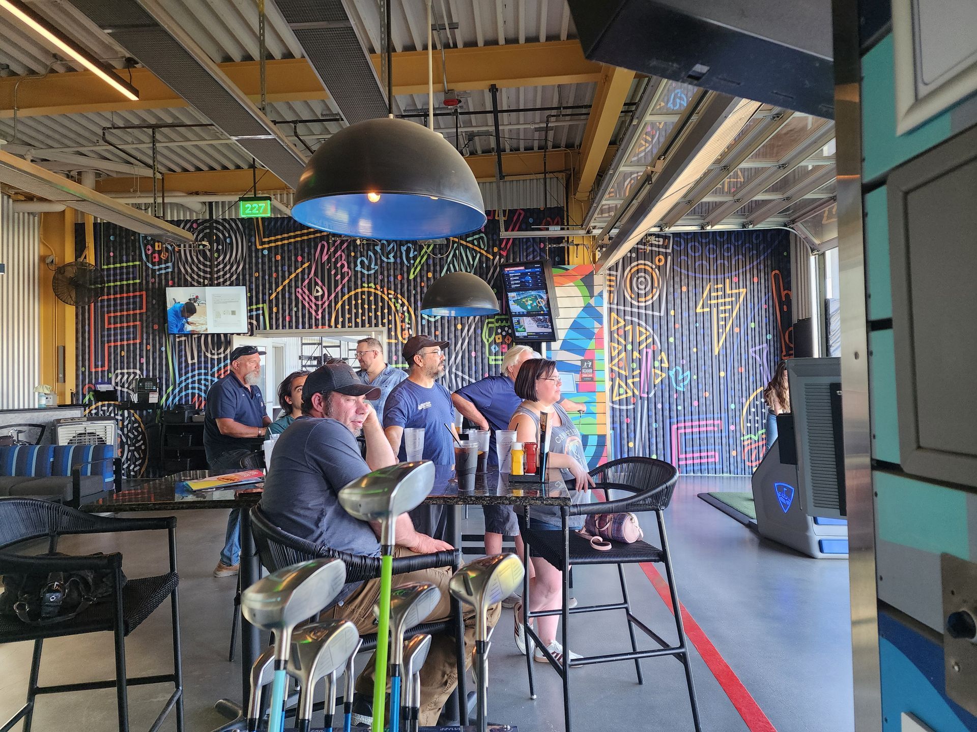 People seated at tables in a colorful indoor café with hanging lights and striped walls.