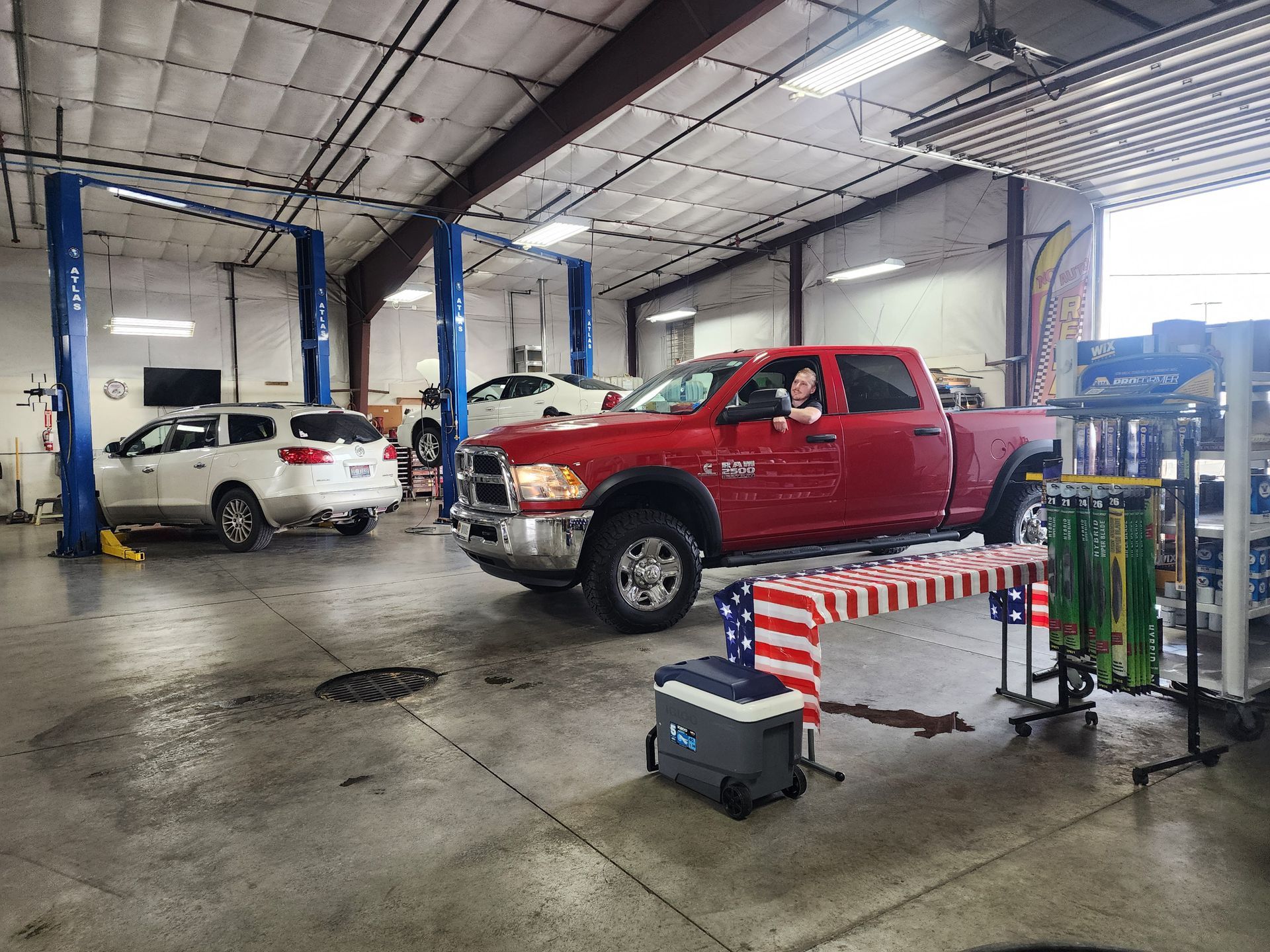 Pickup trucks in a garage, with equipment and a barricade in the foreground.