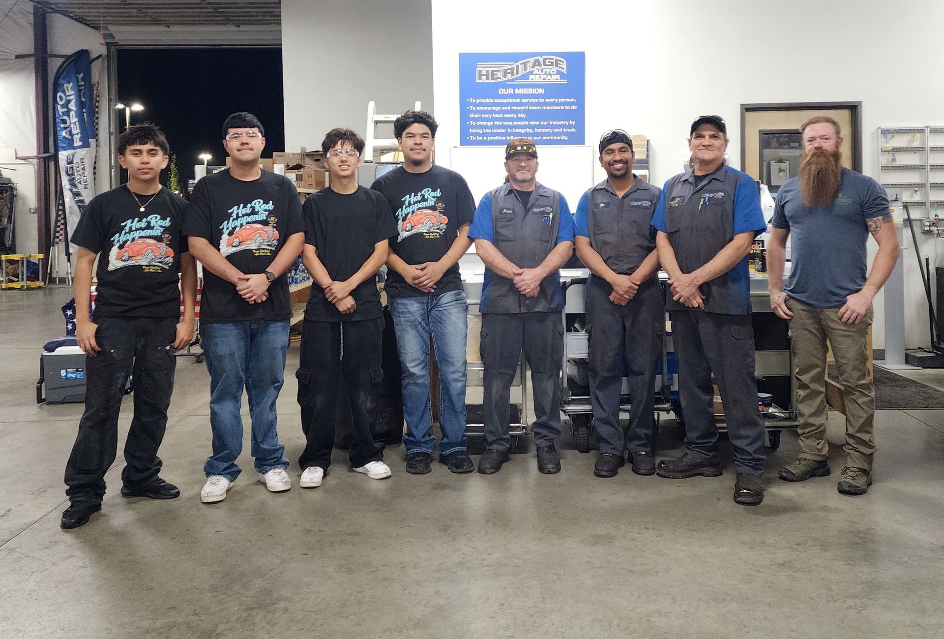 Group of people in matching shirts standing in a workshop, posing for a team photo.