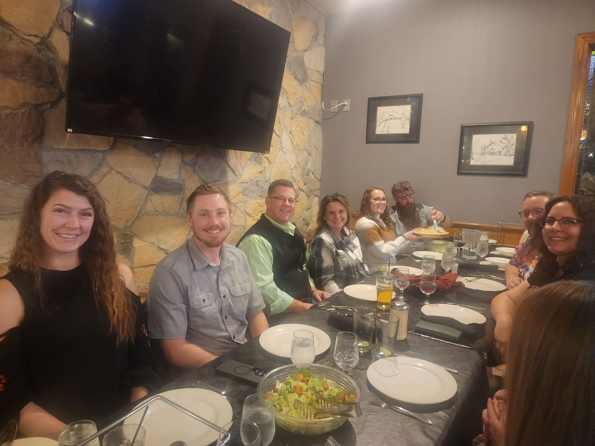 Group of people gathered around a dining table in a restaurant, smiling and eating together.