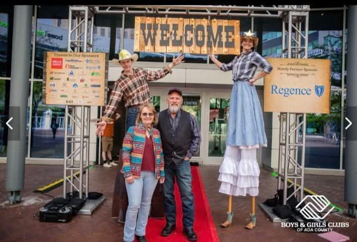 Costumed people posed under a “WELCOME” banner at a Regence event booth with a red carpet entrance.