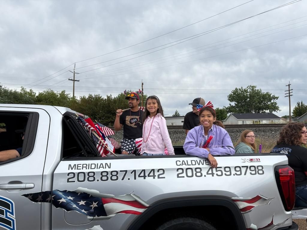 Group standing in a decorated pickup truck at an outdoor parade, with phone numbers on the side.