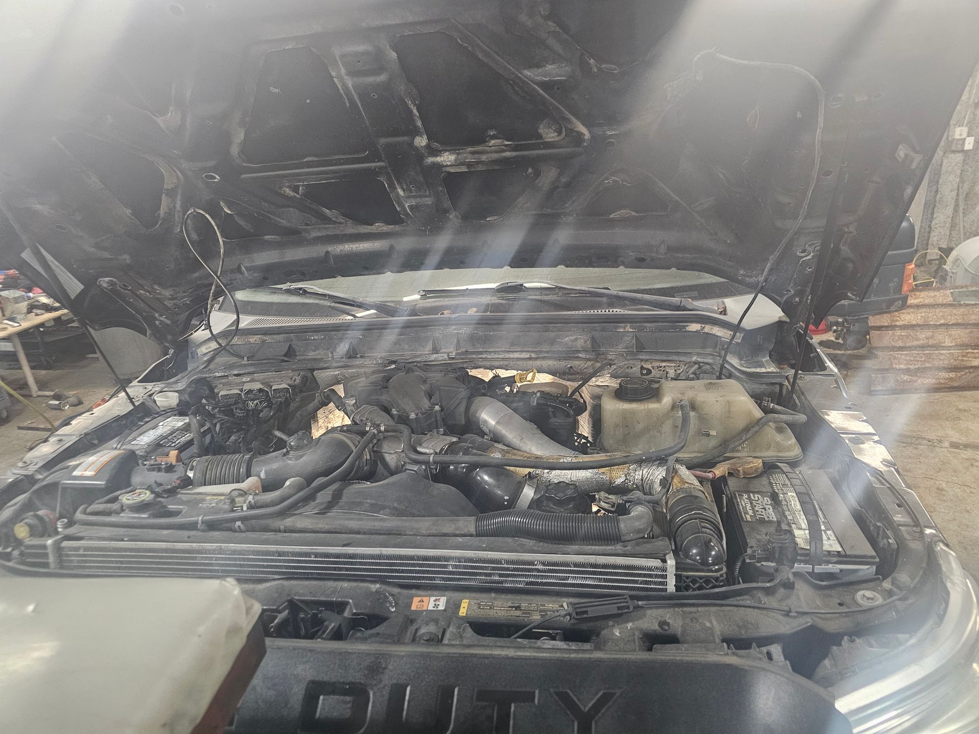 Black truck with open hood, showing engine components.