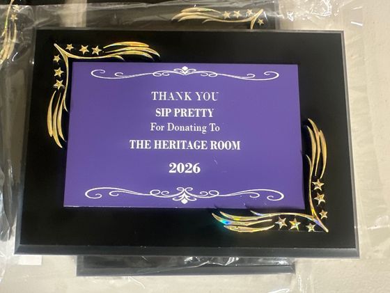 Framed black-and-gold plaque with purple thank-you note for decorating the Heritage Room in 2026
