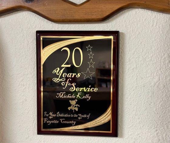 Framed gold-and-burgundy 20 years of service plaque with engraved text on a wall