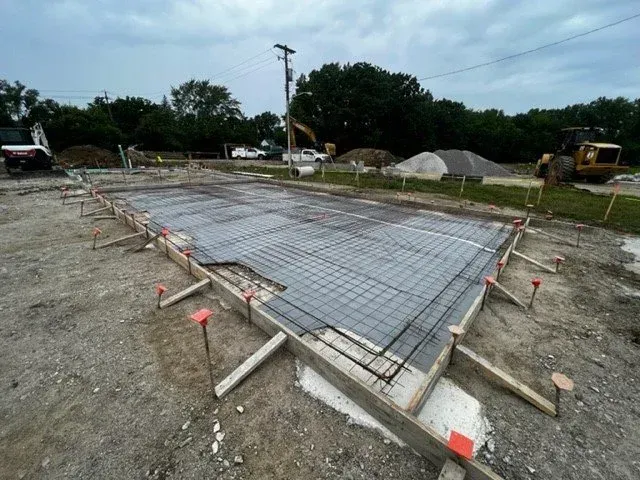 Concrete foundation slab with rebar and wooden forms at a construction site