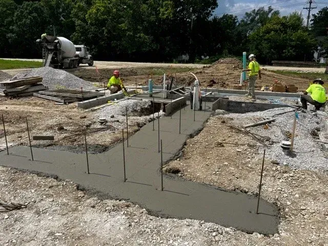 Construction workers pouring concrete for a foundation on a roadwork site