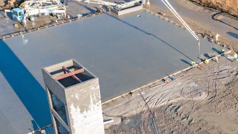 Aerial view of a large concrete construction site with a tall tower and surrounding earthworks