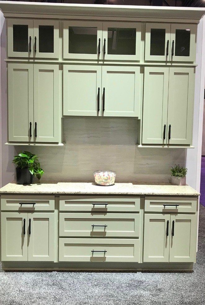 A kitchen with green cabinets and white counter tops