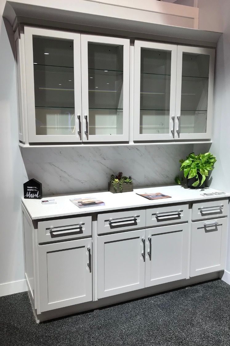 A kitchen with white cabinets and glass doors.
