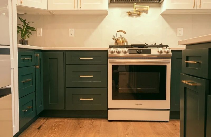 A kitchen with green cabinets and a white stove and oven.