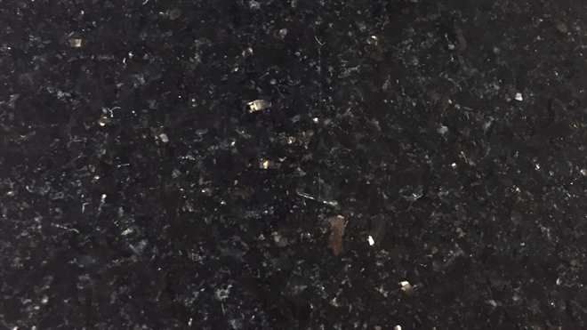 A close up of a black granite counter top with white spots.