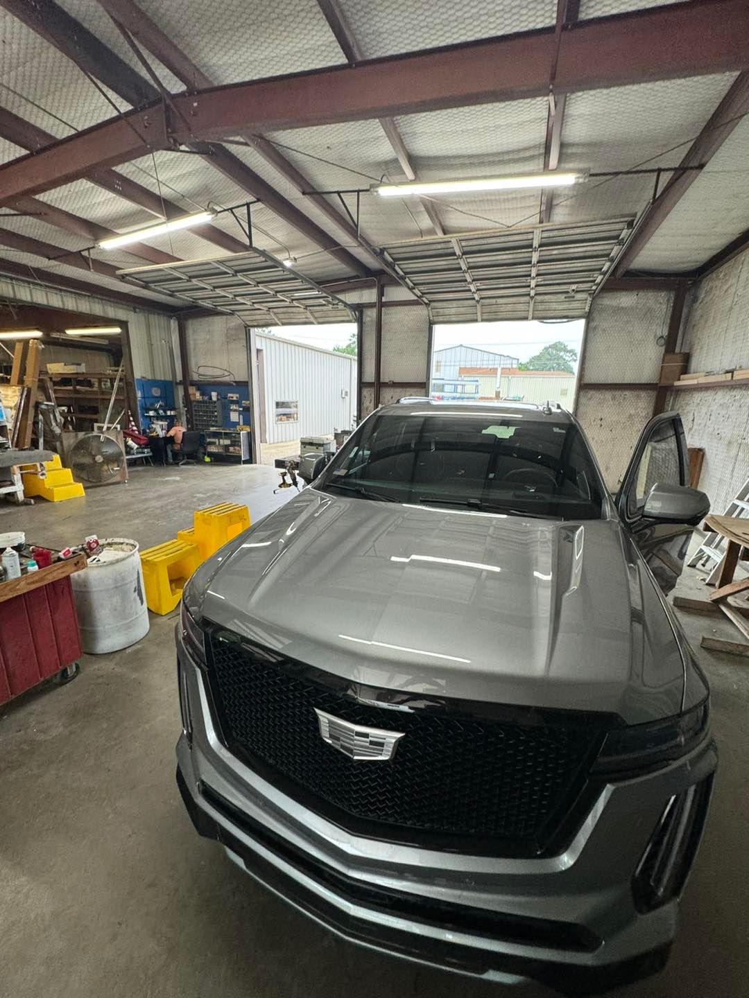 Gray Cadillac SUV parked inside a garage with tools and equipment around it