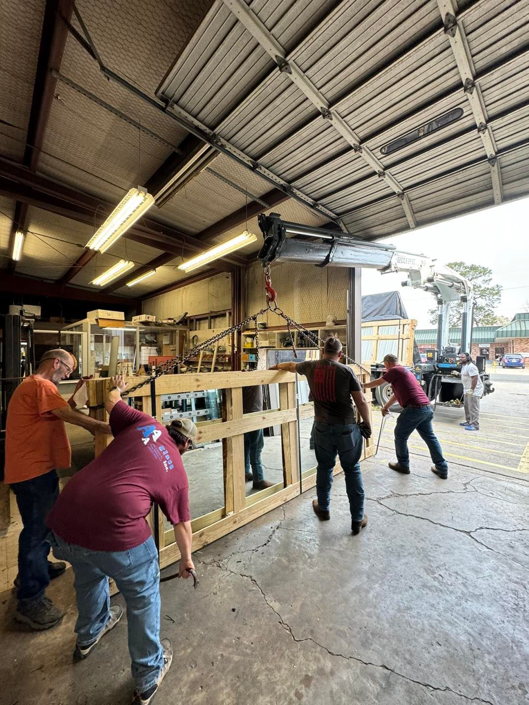 Workers moving a wooden frame in a workshop with open garage doors