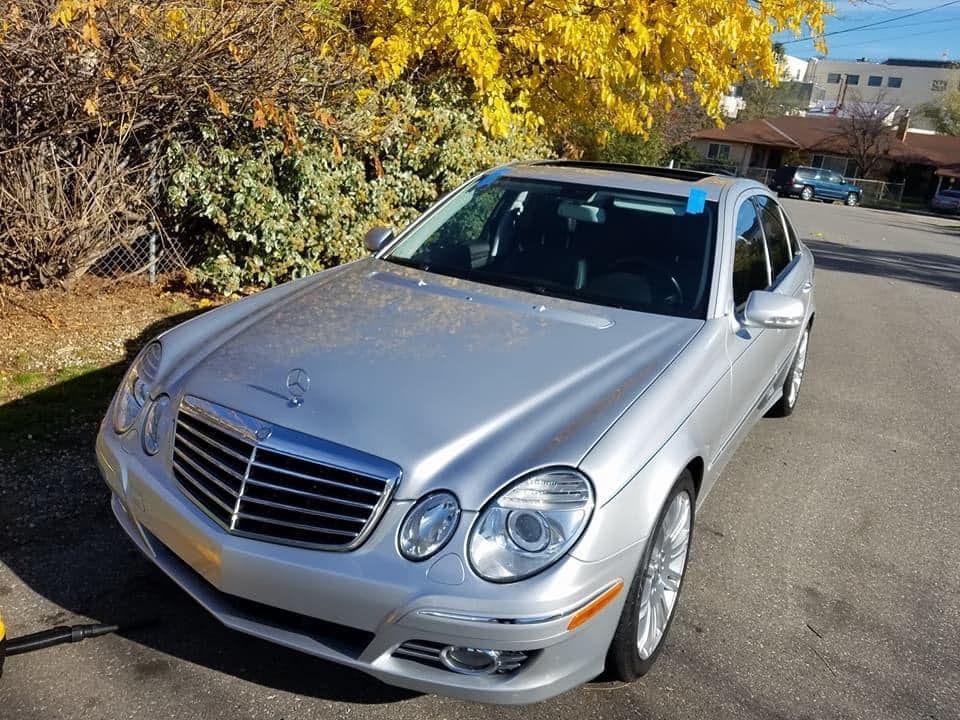 Silver Mercedes sedan parked on a street beside autumn trees
