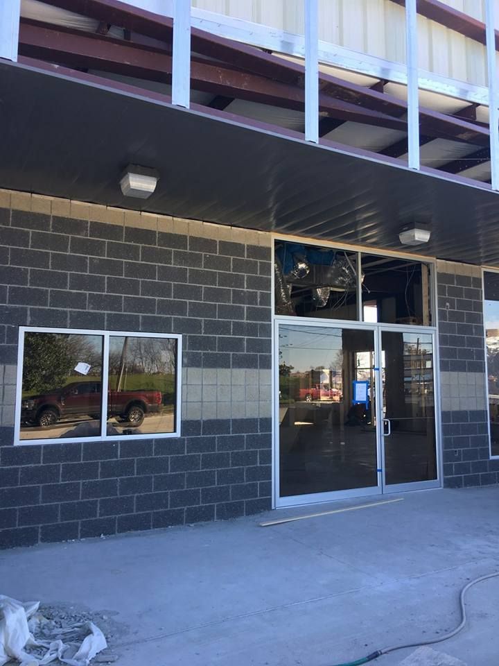 Storefront with black brick facade, glass door, and window beneath a covered overhang.