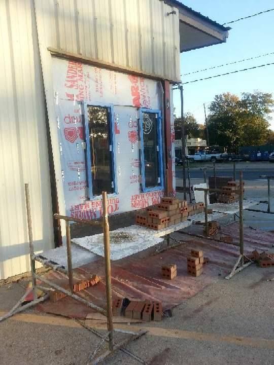 Small building entrance under construction with scaffolding, insulation, and debris on the ground