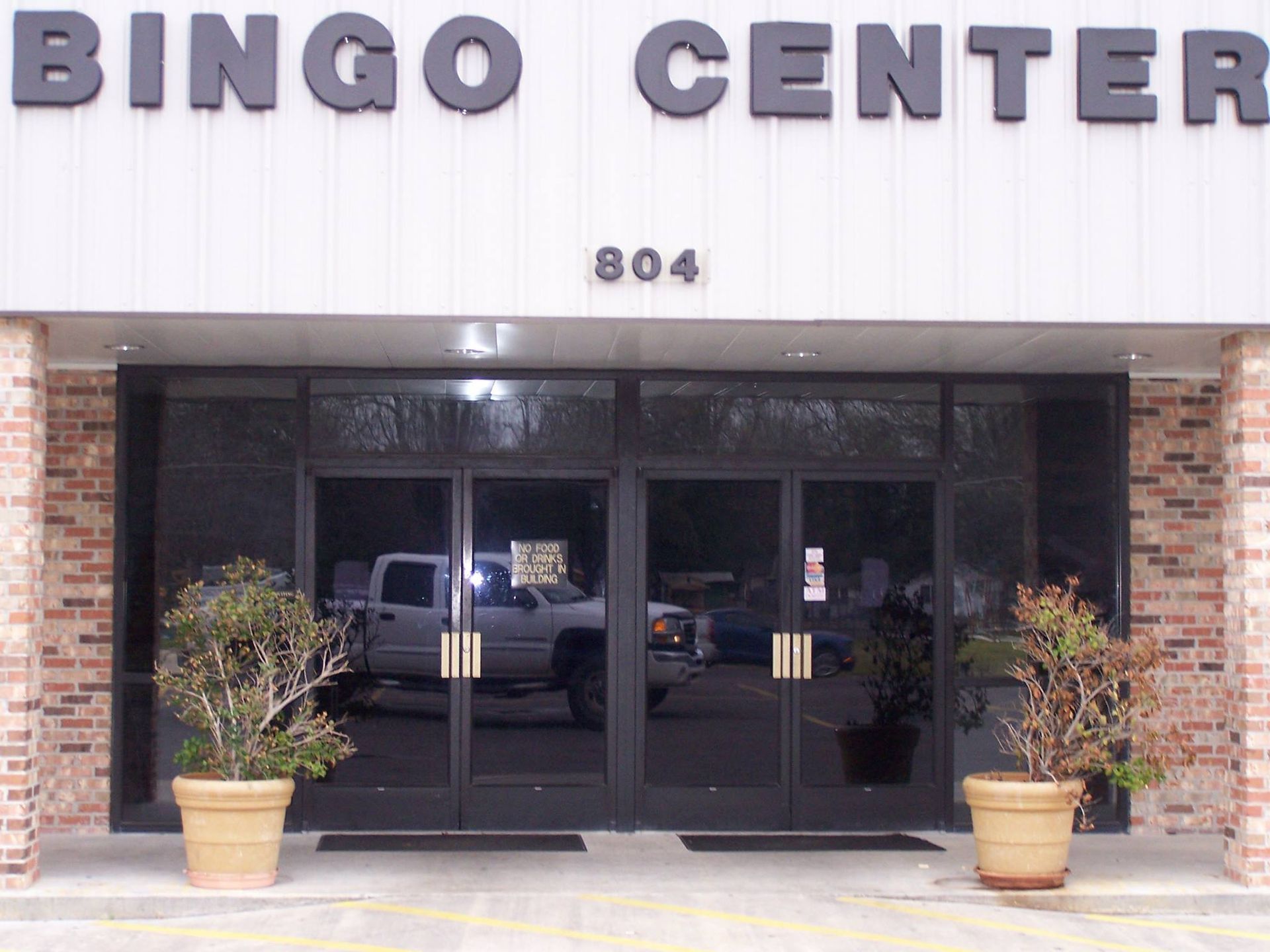 Front entrance of Bingo Center with glass doors, brick walls, potted plants, and address 804.