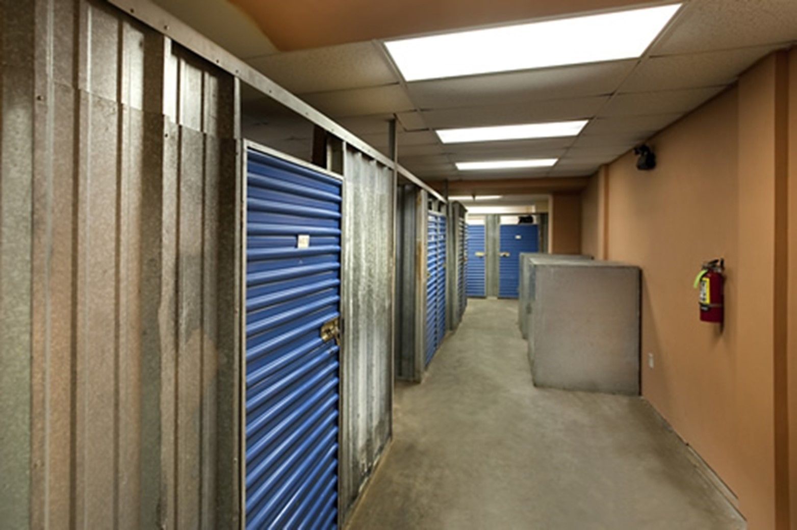 A hallway with blue doors and a fire extinguisher on the wall