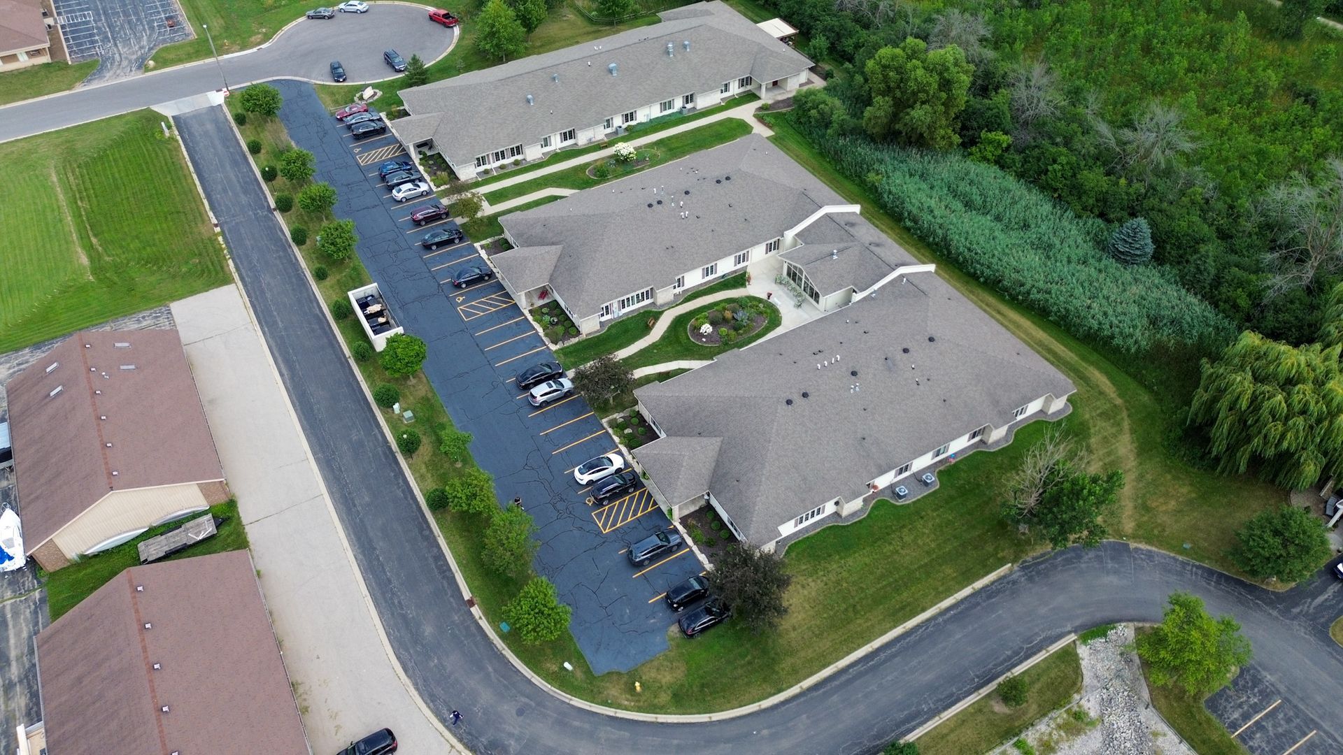 Aerial view of a senior living complex with multiple buildings, parking lot, and green space.