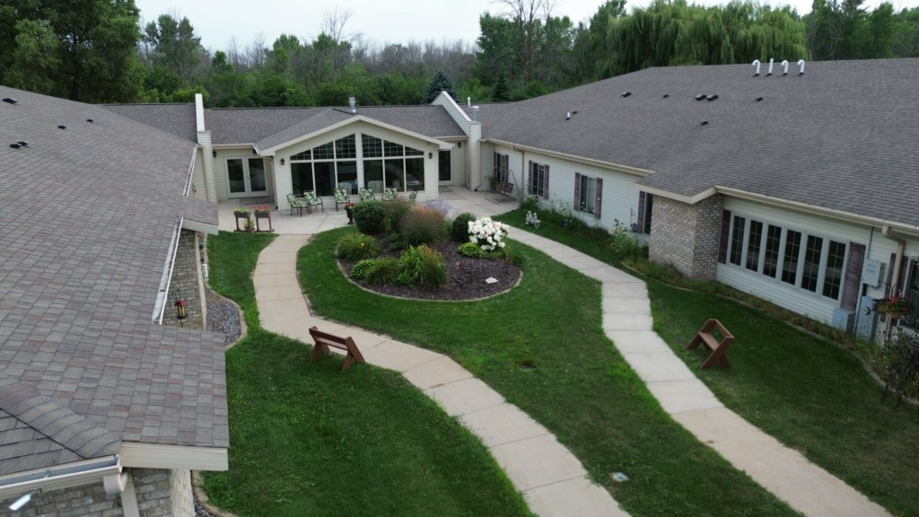 Aerial view of a single-story building with a courtyard, green lawn, and winding sidewalks.
