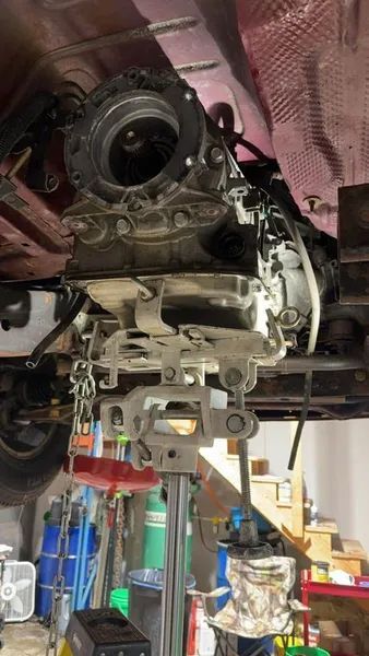 A car engine is sitting on top of a jack in a garage.