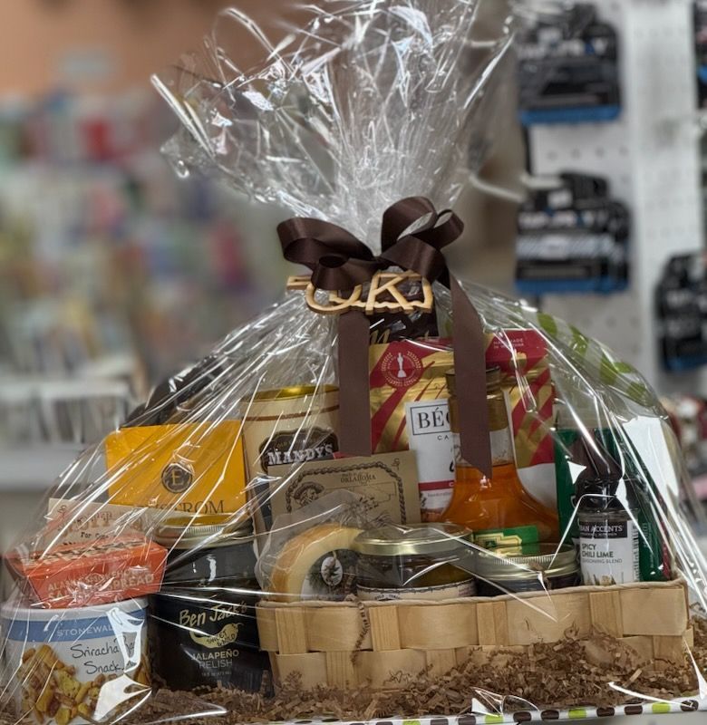 Gift basket with assorted gourmet foods, wrapped in clear cellophane with a brown ribbon bow.