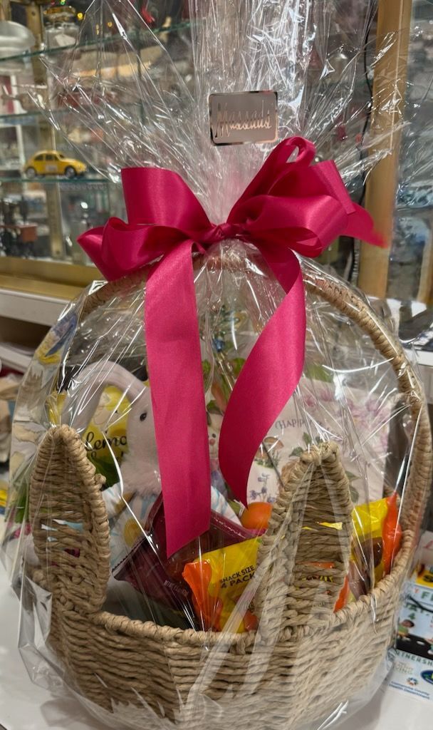 Gift basket wrapped in clear cellophane with a large red bow and assorted snacks inside