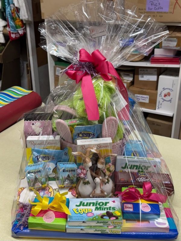 Gift basket display with pink ribbon, colorful candy packages, and stuffed toys on a store counter