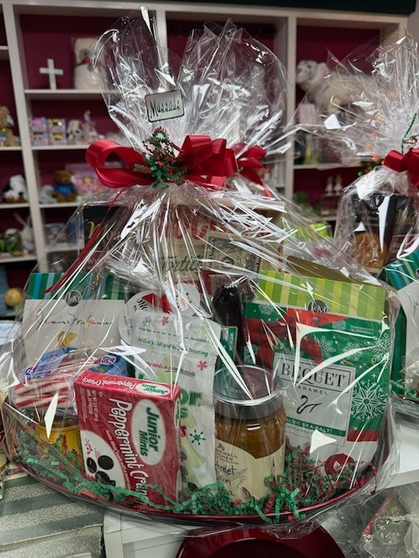 Gift basket with red bow, wrapped in clear cellophane, filled with holiday treats and candy bars