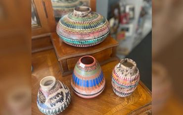Learn More About Us Three colorful vases are sitting on top of a wooden table.