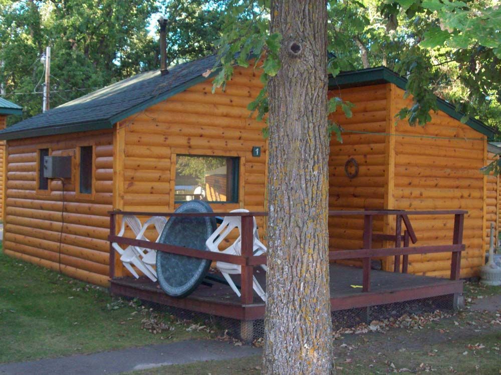 a small log cabin with a porch and chairs