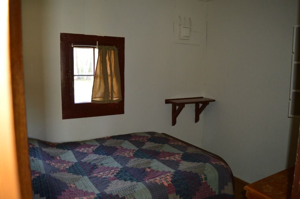 a bedroom with a bed, window and shelf