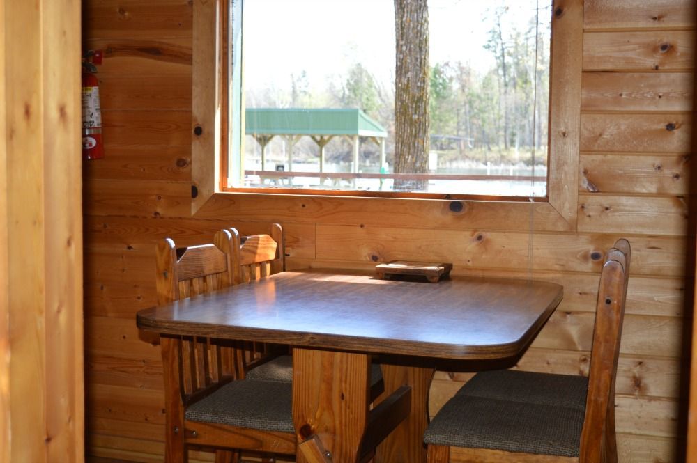 a wooden cabin with a table and chairs in front of a window