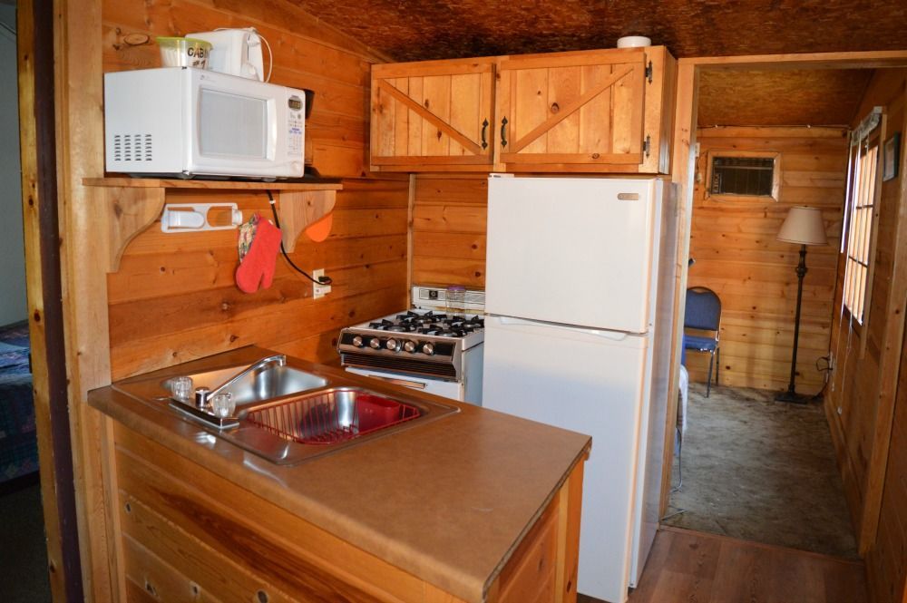 a kitchen with a sink, stove, refrigerator and microwave