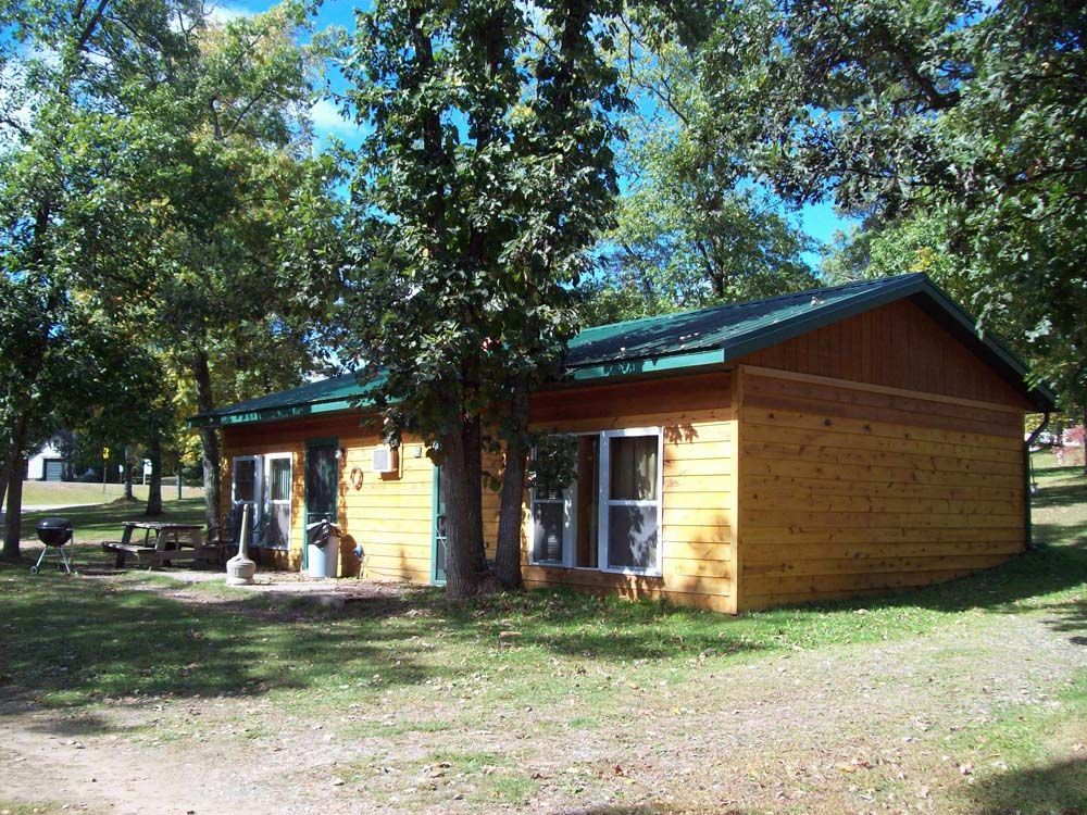 a small wooden house with a green roof is surrounded by trees