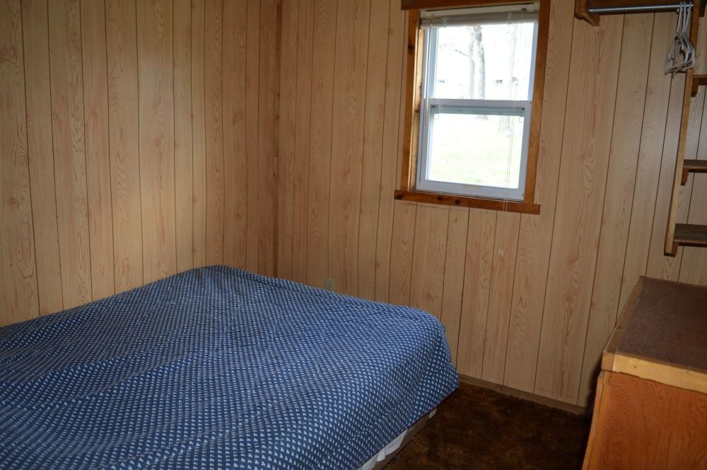 a bedroom with a bed, window and dresser