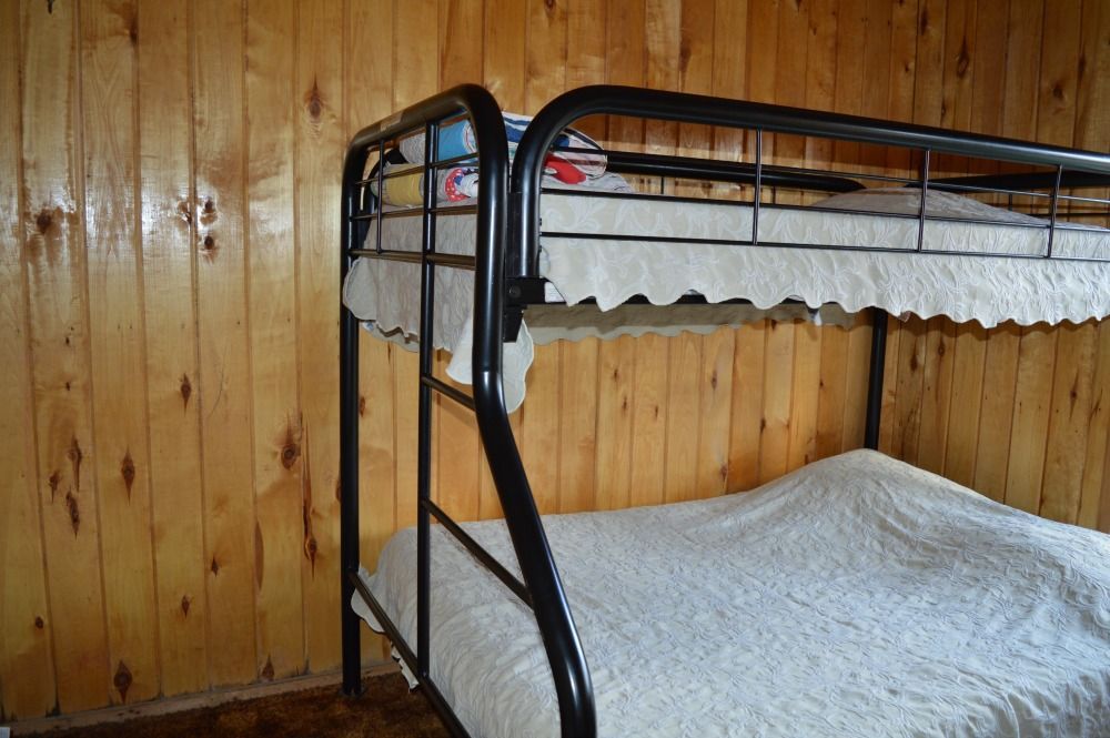 a bunk bed with a white blanket on it in a wooden room
