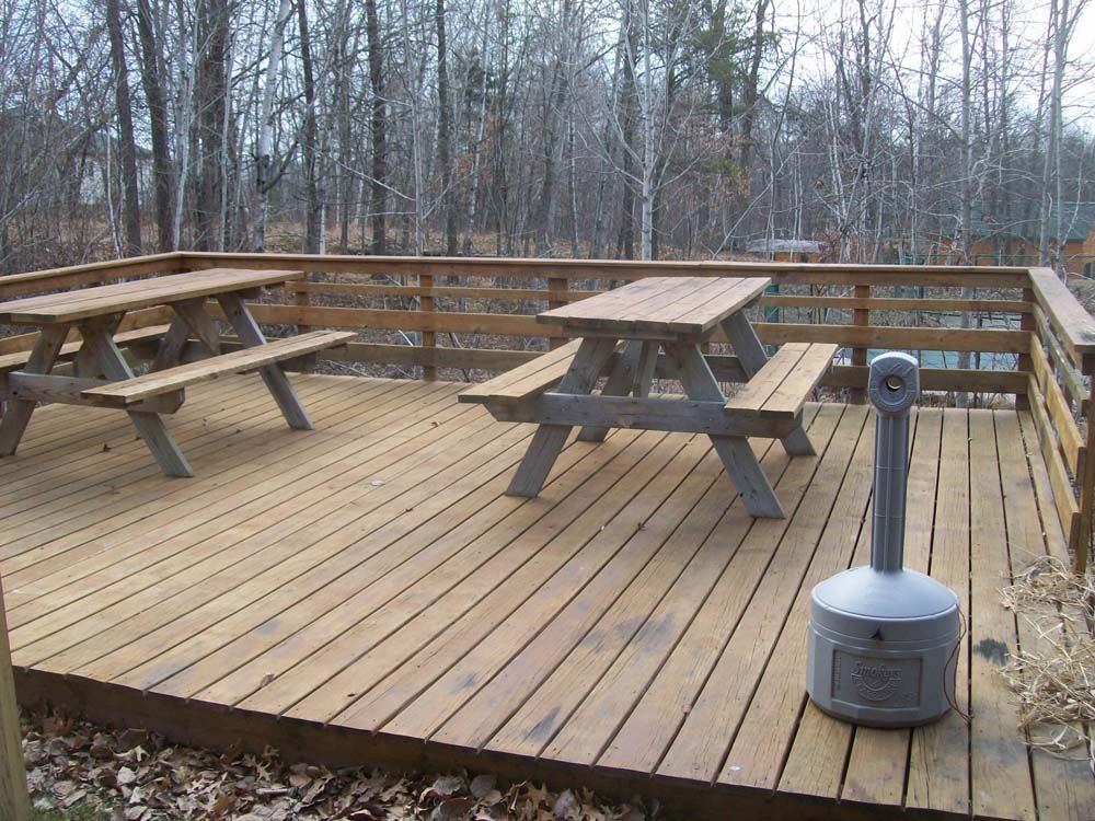 a wooden deck with a picnic table and benches