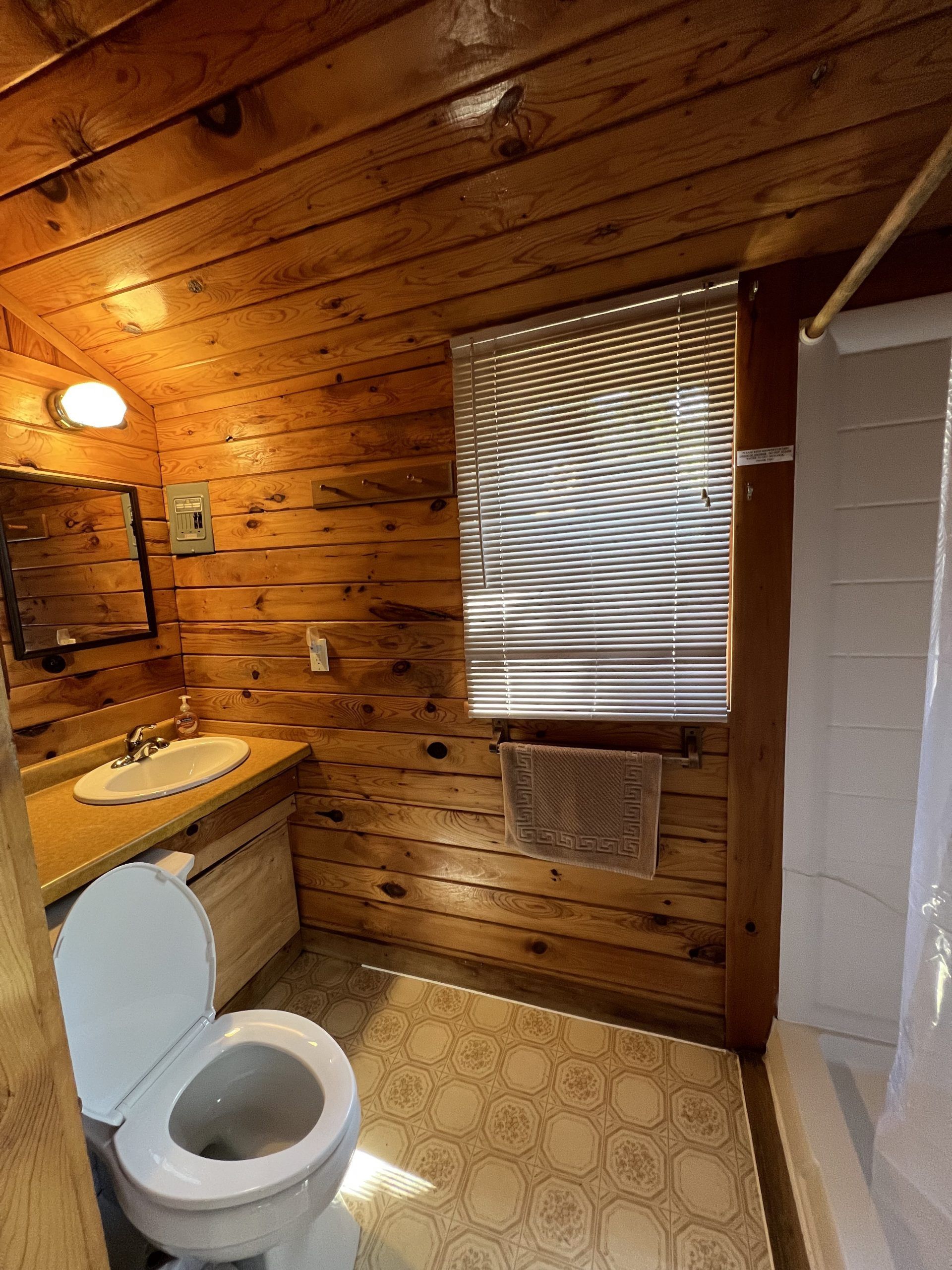 a bathroom in a log cabin with a toilet, sink and shower