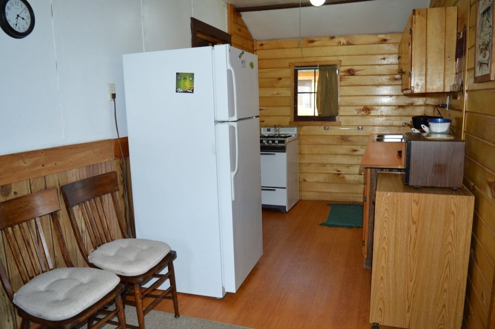 a kitchen with a white refrigerator and two chairs