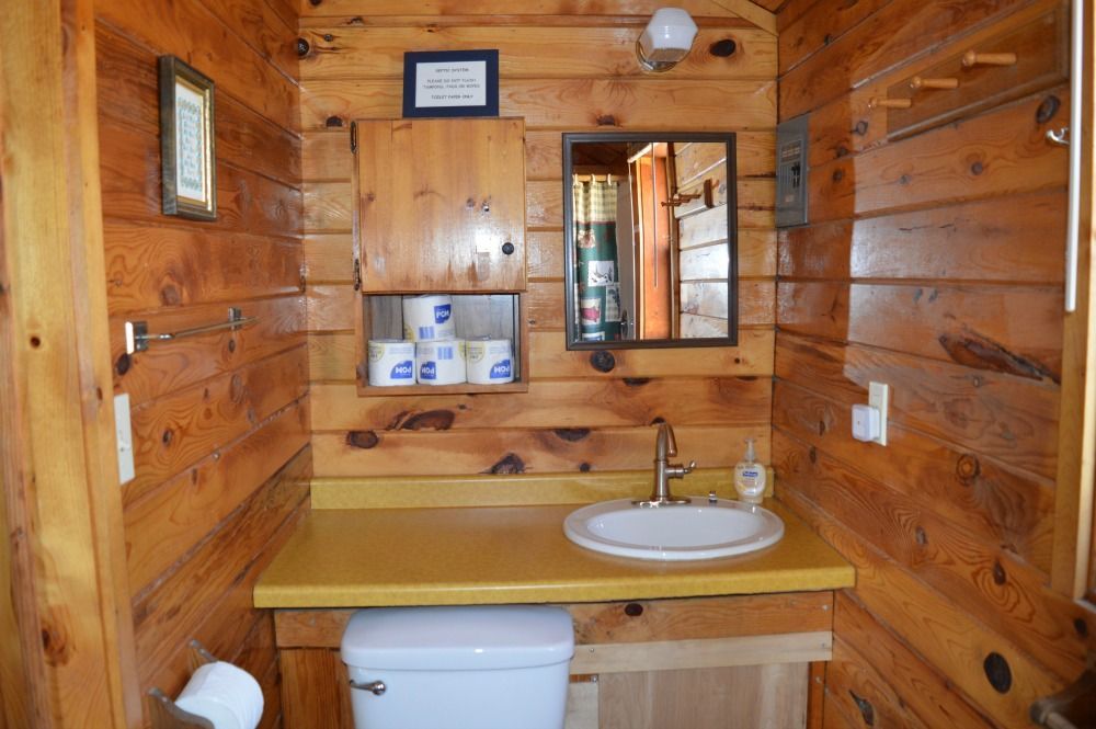 a bathroom in a log cabin with a toilet, sink and mirror