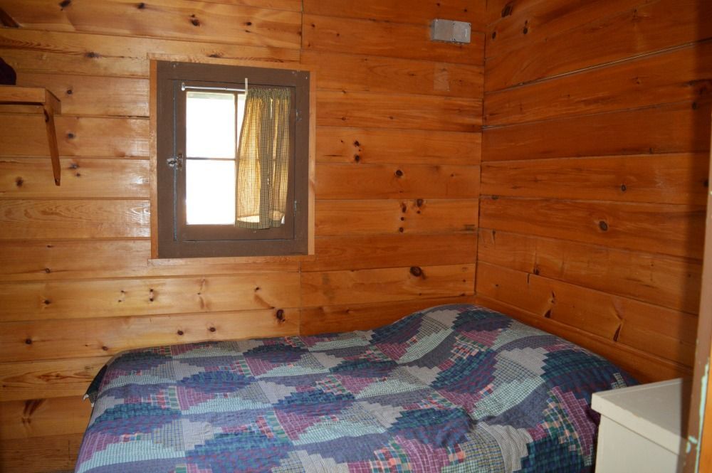 a bedroom in a log cabin with a bed and a window