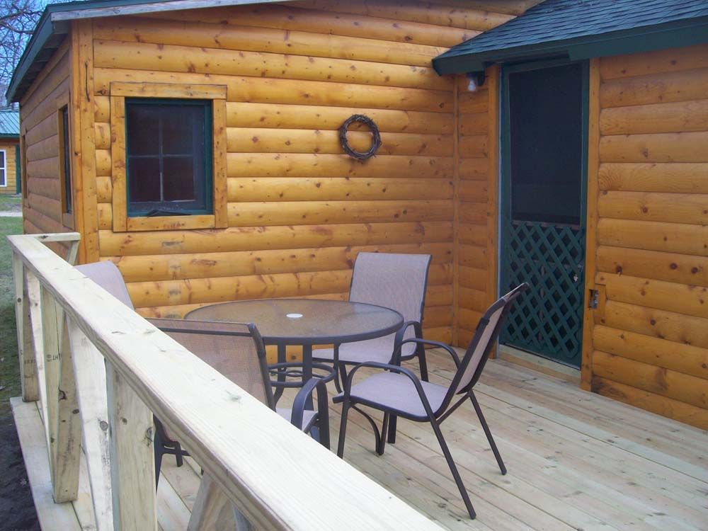 a wooden cabin with a table and chairs on the deck