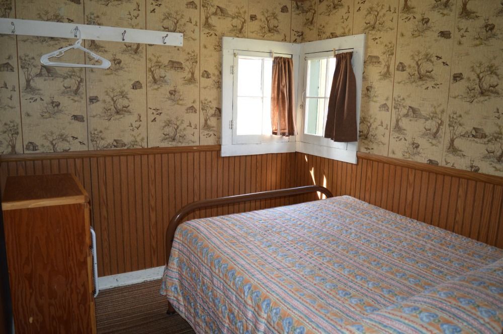 a bedroom with a bed, dresser, and window