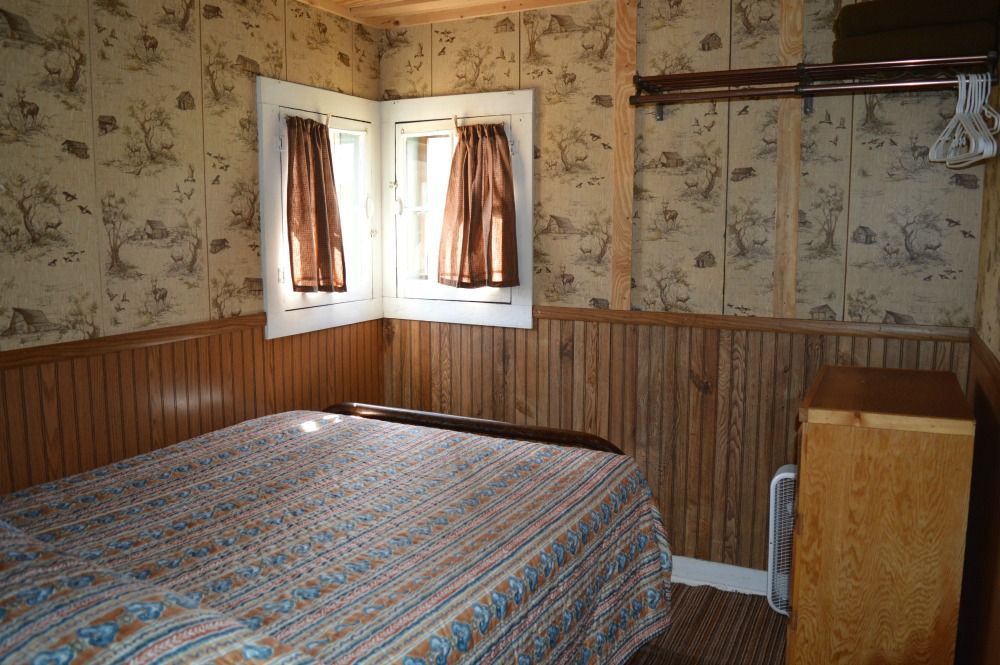 a bedroom with a bed, dresser, and window